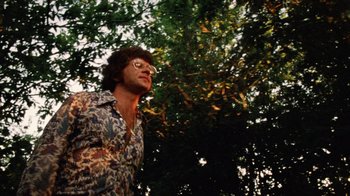 Movie still from “The Texas Chain Saw Massacre” (1974), directed by Tobe Hooper – A man with glasses standing in front of a tree; Medium shot, Low angle