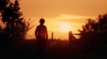 Movie still from “The Texas Chain Saw Massacre” (1974), directed by Tobe Hooper – A person standing in a field with a sunset in the background; Wide shot, Low angle