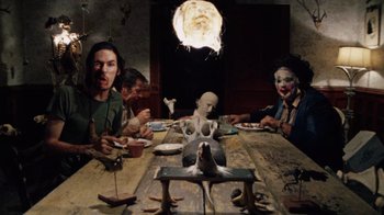 Movie still from “The Texas Chain Saw Massacre” (1974), directed by Tobe Hooper – A group of people sitting around a table; Wide shot, Low angle