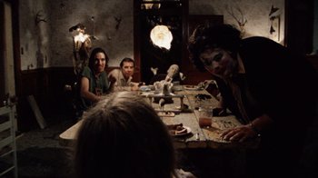 Movie still from “The Texas Chain Saw Massacre” (1974), directed by Tobe Hooper – A group of people sitting around a table; Wide shot, Over the shoulder angle