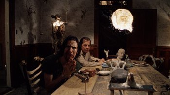 Movie still from “The Texas Chain Saw Massacre” (1974), directed by Tobe Hooper – Two people sitting at a dinner table eating food; Medium shot, Low angle