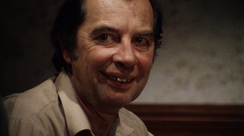 Movie still from “The Texas Chain Saw Massacre” (1974), directed by Tobe Hooper – A person smiling for the camera; Close Up shot, Over the shoulder angle