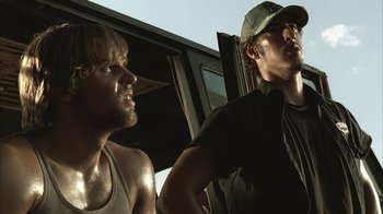 Two men standing next to each other in front of a truck