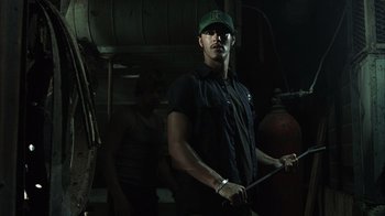 Movie still from “The Texas Chainsaw Massacre” (2003), directed by Marcus Nispel – A man holding a baseball bat while standing next to another man; Medium shot, Low angle