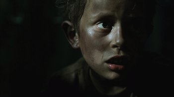 Movie still from “The Texas Chainsaw Massacre” (2003), directed by Marcus Nispel – A young boy's face in the dark; Close Up shot, Low angle