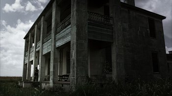Movie still from “The Texas Chainsaw Massacre” (2003), directed by Marcus Nispel – An abandoned building with a bench in front of it; Extreme Wide shot, Low angle