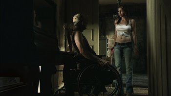 Movie still from “The Texas Chainsaw Massacre” (2003), directed by Marcus Nispel – A man sitting in a wheel chair next to a woman; Medium shot, Low angle