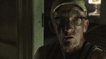 Movie still from “The Texas Chainsaw Massacre” (2003), directed by Marcus Nispel – An old man wearing glasses and a hat; Close Up shot, Low angle