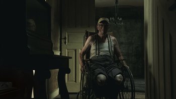 Movie still from “The Texas Chainsaw Massacre” (2003), directed by Marcus Nispel – An old man sitting in a wheel chair in a dark room; Wide shot, Low angle