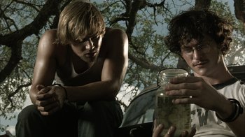 Movie still from “The Texas Chainsaw Massacre” (2003), directed by Marcus Nispel – Two young men are looking at a jar of water; Close Up shot, Low angle