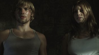 Movie still from “The Texas Chainsaw Massacre” (2003), directed by Marcus Nispel – A man and a woman standing next to each other in front of a brick wall; Close Up shot, Low angle