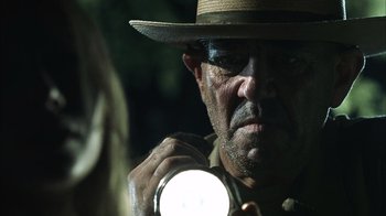 Movie still from “The Texas Chainsaw Massacre” (2003), directed by Marcus Nispel – A man with a hat and a flashlight in his hand; Close Up shot, Over the shoulder angle