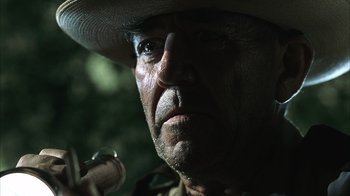 Movie still from “The Texas Chainsaw Massacre” (2003), directed by Marcus Nispel – A person wearing a cowboy hat and holding a pipe; Extreme Close Up shot, Low angle