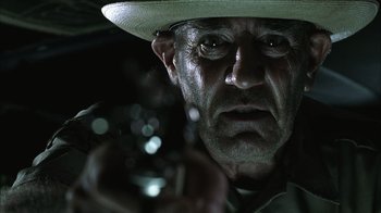 Movie still from “The Texas Chainsaw Massacre” (2003), directed by Marcus Nispel – An old man with a hat holding a wine glass; Close Up shot, Low angle