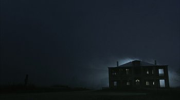 Movie still from “The Texas Chainsaw Massacre” (2003), directed by Marcus Nispel – A house is lit up at night in the dark sky; Extreme Wide shot, Low angle