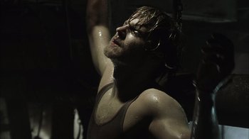 Movie still from “The Texas Chainsaw Massacre” (2003), directed by Marcus Nispel – A man in a tank top with his arms up; Close Up shot, Low angle