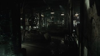 Movie still from “The Texas Chainsaw Massacre” (2003), directed by Marcus Nispel – A room filled with lots of furniture in the dark; Extreme Wide shot, High angle