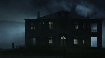 Movie still from “The Texas Chainsaw Massacre” (2003), directed by Marcus Nispel – A dark building with lights shining on it's windows; Extreme Wide shot, Low angle
