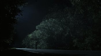 Movie still from “The Texas Chainsaw Massacre” (2003), directed by Marcus Nispel – A person standing on the side of a road at night; Extreme Wide shot, Low angle