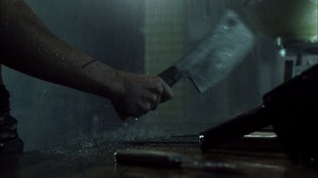 Movie still from “The Texas Chainsaw Massacre” (2003), directed by Marcus Nispel – A person is holding a meat cleaver in the rain; Extreme Close Up shot, Overhead angle
