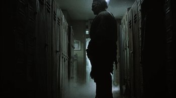 Movie still from “The Texas Chainsaw Massacre” (2003), directed by Marcus Nispel – A man standing next to a row of lockers in a room; Medium shot, Low angle