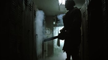 Movie still from “The Texas Chainsaw Massacre” (2003), directed by Marcus Nispel – A person holding a fire extinguisher in a room; Wide shot, Low angle