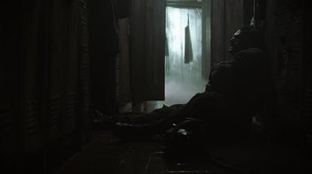 Movie still from “The Texas Chainsaw Massacre” (2003), directed by Marcus Nispel – A person sitting on the ground in a room; Wide shot, Low angle