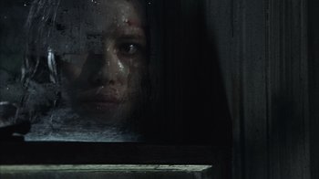 Movie still from “The Texas Chainsaw Massacre” (2003), directed by Marcus Nispel – A woman looking out of a window at night with blood on her face; Close Up shot, Low angle