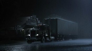 Movie still from “The Texas Chainsaw Massacre” (2003), directed by Marcus Nispel – A semi truck driving down a street in the rain at night; Extreme Wide shot, Low angle
