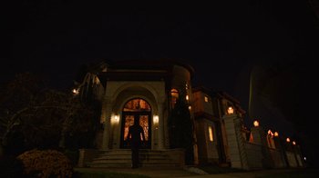 Movie still from “Full Circle” (2023), directed by Steven Soderbergh – A person standing in front of a building at night; Extreme Wide shot, Low angle