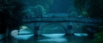 Movie still from “The Theory of Everything” (2014), directed by James Marsh – Two people standing on a bridge over a body of water at night; Extreme Wide shot, High angle