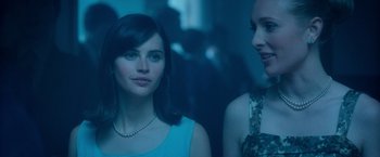 Movie still from “The Theory of Everything” (2014), directed by James Marsh – Two young women standing next to each other in a dark room; Close Up shot, Over the shoulder angle