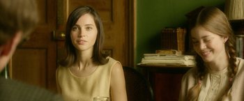 Movie still from “The Theory of Everything” (2014), directed by James Marsh – A woman sitting at a table with a glass of water; Close Up shot, Over the shoulder angle