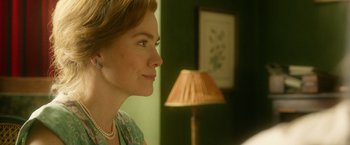 Movie still from “The Theory of Everything” (2014), directed by James Marsh – A woman is looking into the distance in front of a lamp in a green room; Close Up shot, Over the shoulder angle