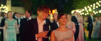 Movie still from “The Theory of Everything” (2014), directed by James Marsh – A man and a woman are standing next to each other; Medium shot, Over the shoulder angle