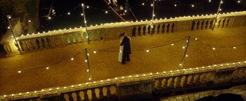 Movie still from “The Theory of Everything” (2014), directed by James Marsh – Two people standing on a balcony at night with lights; Extreme Wide shot, Overhead angle