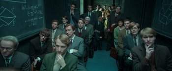 Movie still from “The Theory of Everything” (2014), directed by James Marsh – A group of men and women sitting in a room; Medium shot, High angle