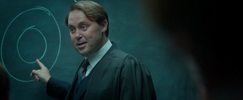 Movie still from “The Theory of Everything” (2014), directed by James Marsh – A man in a robe and tie standing in front of a green wall; Close Up shot, Over the shoulder angle