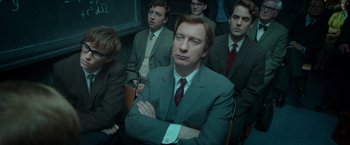 Movie still from “The Theory of Everything” (2014), directed by James Marsh – A group of men in suits and ties sitting in a room; Medium shot, Over the shoulder angle