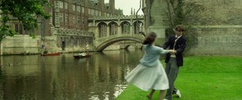 Movie still from “The Theory of Everything” (2014), directed by James Marsh – A girl in a white dress and a man in a blue jacket are by a river; Wide shot, High angle
