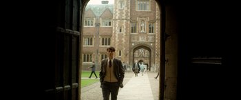 Movie still from “The Theory of Everything” (2014), directed by James Marsh – A man in a suit standing in front of an archway; Wide shot, Low angle