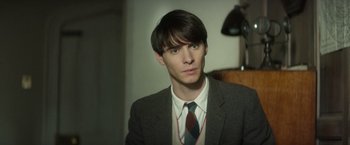 Movie still from “The Theory of Everything” (2014), directed by James Marsh – A man in a suit and tie looking at the camera; Close Up shot, Over the shoulder angle