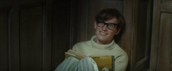 Movie still from “The Theory of Everything” (2014), directed by James Marsh – A man sitting on the floor reading a book; Medium shot, Over the shoulder angle