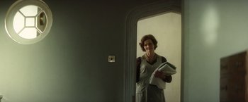 Movie still from “The Theory of Everything” (2014), directed by James Marsh – A woman standing in front of a door holding papers; Medium shot, Low angle