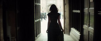 Movie still from “The Theory of Everything” (2014), directed by James Marsh – A woman in a black dress walking through an archway; Medium shot, Over the shoulder angle