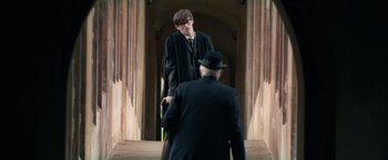 Movie still from “The Theory of Everything” (2014), directed by James Marsh – A man in a suit and tie standing next to another man in a suit and tie; Medium shot, Over the shoulder angle