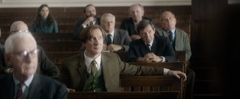 Movie still from “The Theory of Everything” (2014), directed by James Marsh – A group of men in suits and ties sitting in a courtroom; Medium shot, Over the shoulder angle