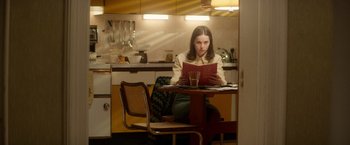 Movie still from “The Theory of Everything” (2014), directed by James Marsh – A woman sitting at a table reading a menu; Medium shot, High angle