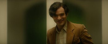 Movie still from “The Theory of Everything” (2014), directed by James Marsh – A man in a brown jacket smiling for the camera; Close Up shot, Over the shoulder angle