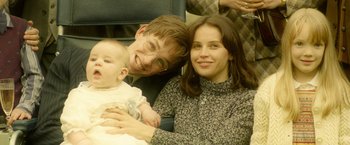 Movie still from “The Theory of Everything” (2014), directed by James Marsh – A man and a woman holding a baby on a train; Close Up shot, Overhead angle